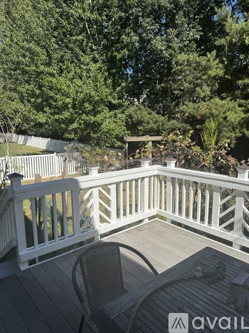 A balcony with a table and chairs overlooking a garden.