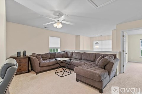A living room with a brown sectional sofa and a white ceiling fan.