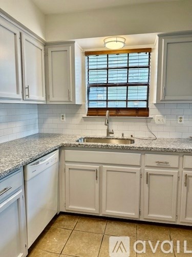 A kitchen with white cabinets and a granite countertop.