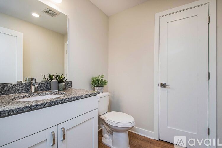A bathroom with a toilet, sink, and mirror.