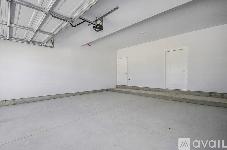 A spacious room with a white ceiling and two white doors.
