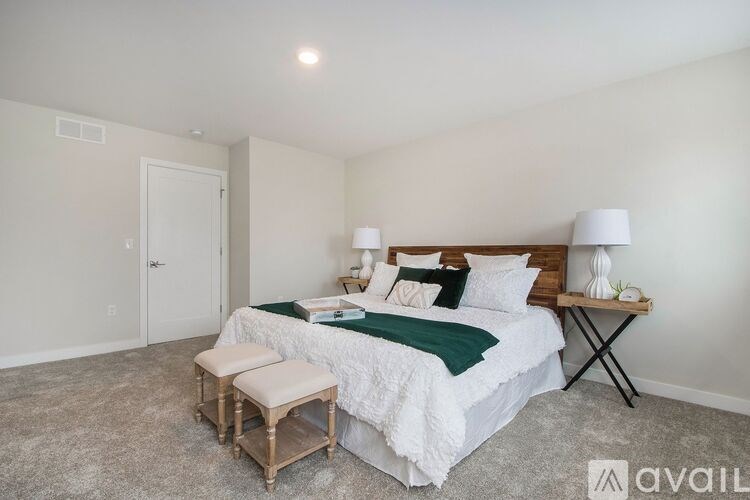 A bedroom with a bed, two lamps, and a bench.