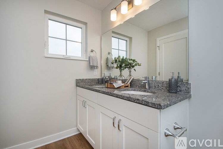 A bathroom with a granite countertop and a large mirror above it.
