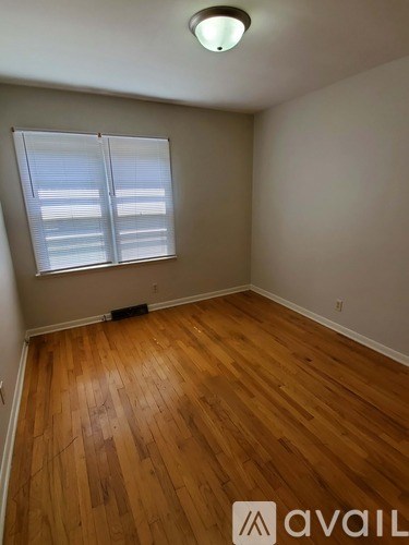 A room with wooden flooring and a window with blinds.