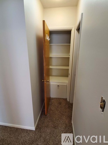 A small, empty room with a carpeted floor and a wooden door.