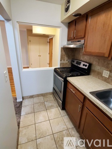 A kitchen with a stove, sink, and cabinets.