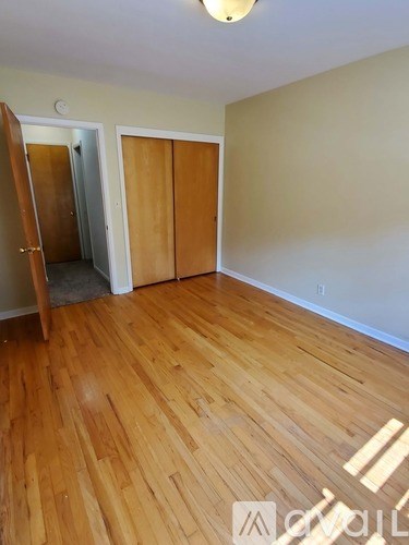 A room with wood flooring and a white wall.