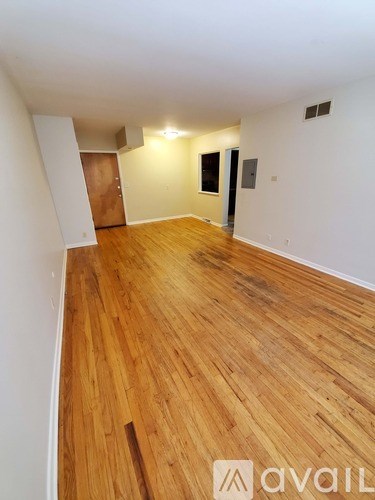 A room with wooden flooring and white walls.