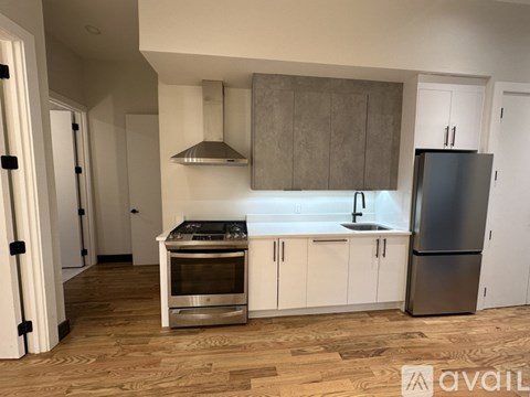 A modern kitchen with wooden floors and stainless steel appliances.