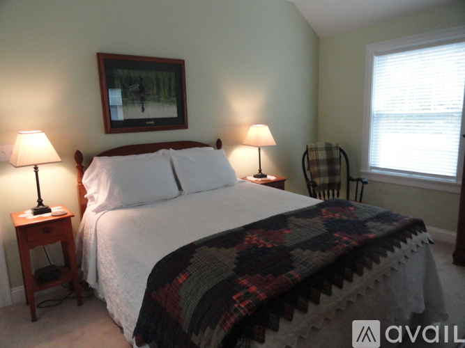 A bedroom with a bed, two lamps, and a picture on the wall.