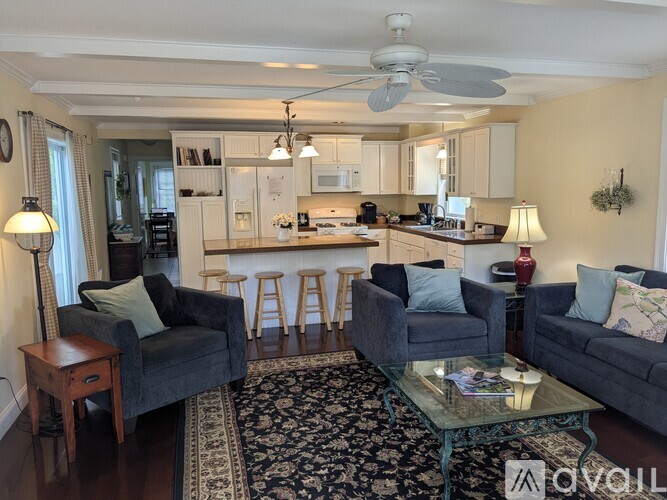 A living room with a grey couch, a black chair, and a glass coffee table.