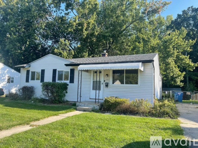A white house with a black roof and a small porch.