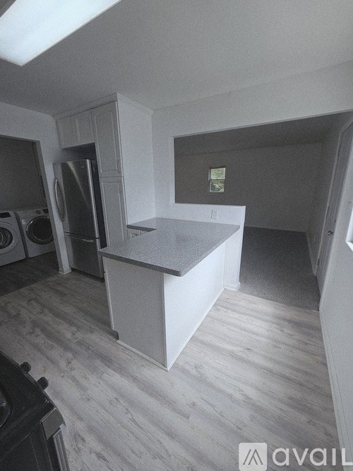 A kitchen with a refrigerator, washing machine, and dryer.