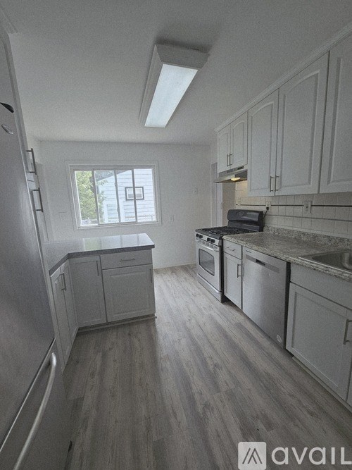A kitchen with white cabinets and a window.