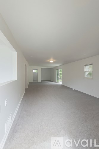 A spacious room with a carpeted floor and white walls.