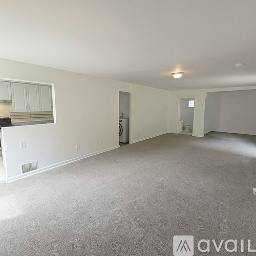 A spacious room with a carpeted floor and a window.
