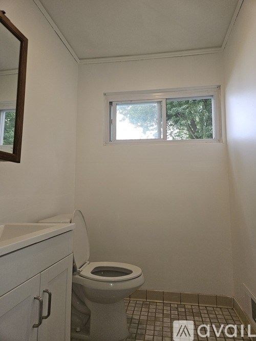 A white toilet in a small bathroom with a window.