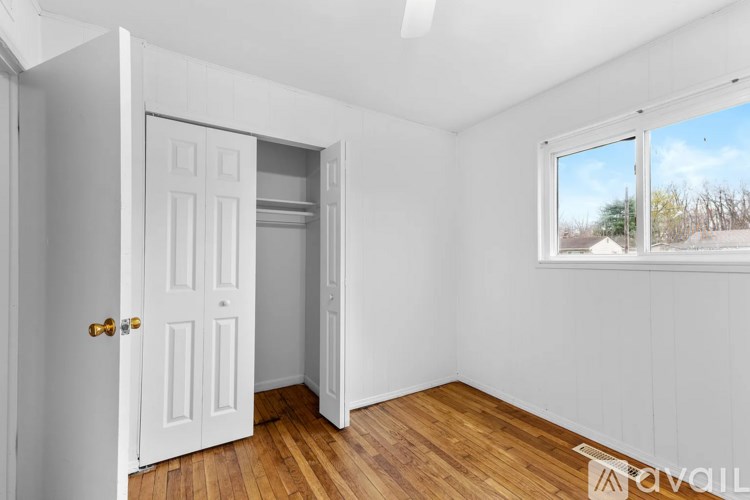 A room with a white door and a window with a view of trees outside.