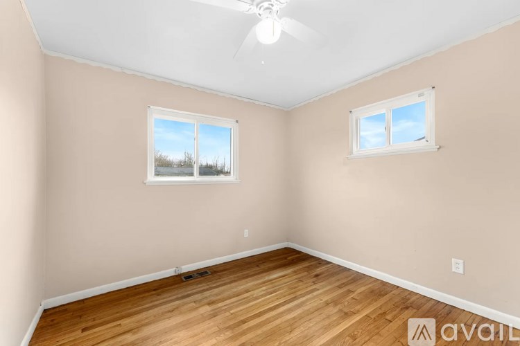 A room with wooden floors and two windows.
