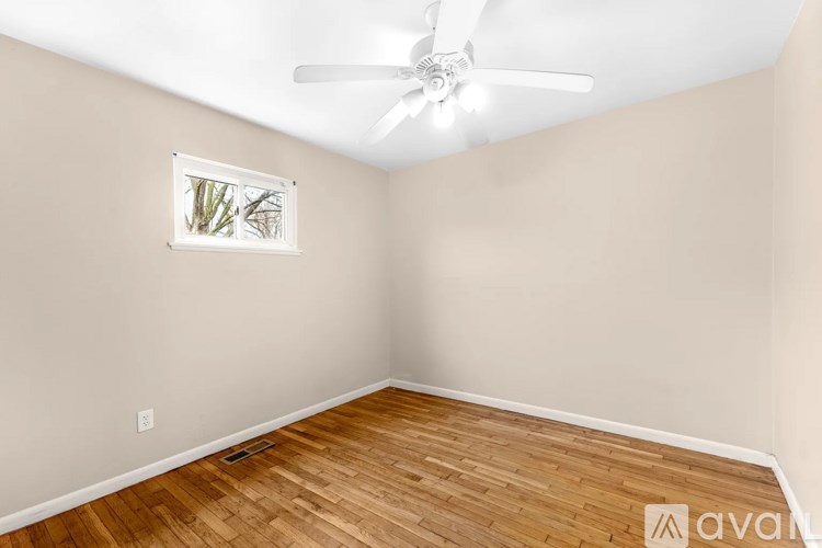 A room with a ceiling fan and wooden flooring.