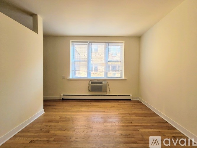 A room with wooden floors and a window with blinds.