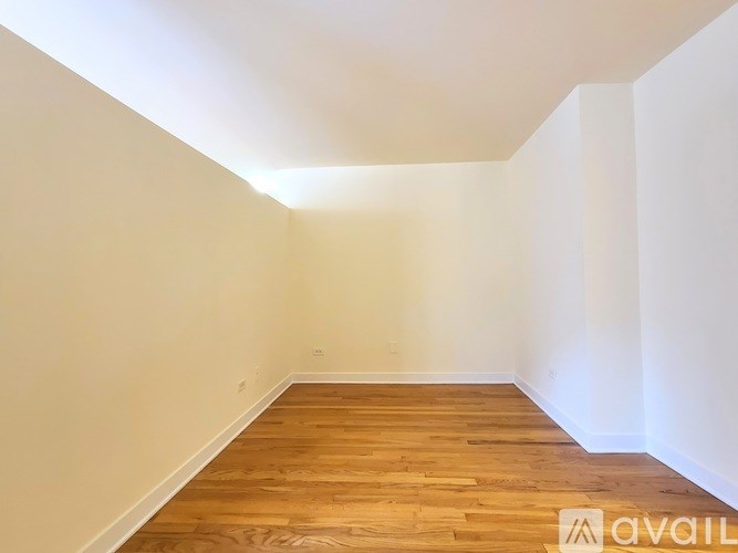Empty room with wooden flooring and white walls.