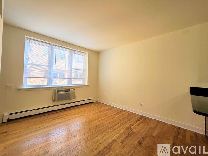 A room with wooden floors and a window with blinds.