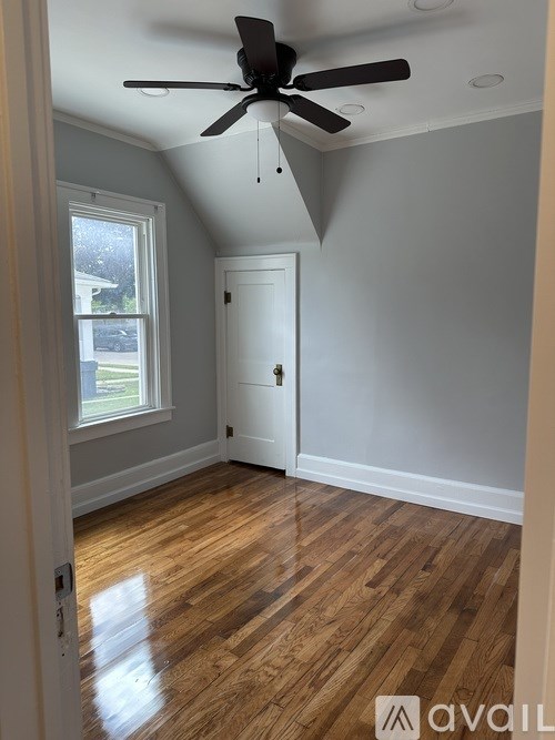 A room with a ceiling fan and wooden flooring.