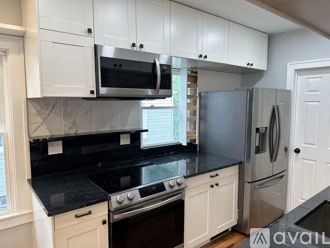 A kitchen with white cabinets and black countertops.