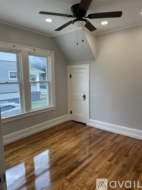 A room with a ceiling fan and wooden flooring.