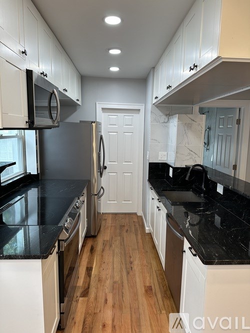 A kitchen with white cabinets and black countertops.