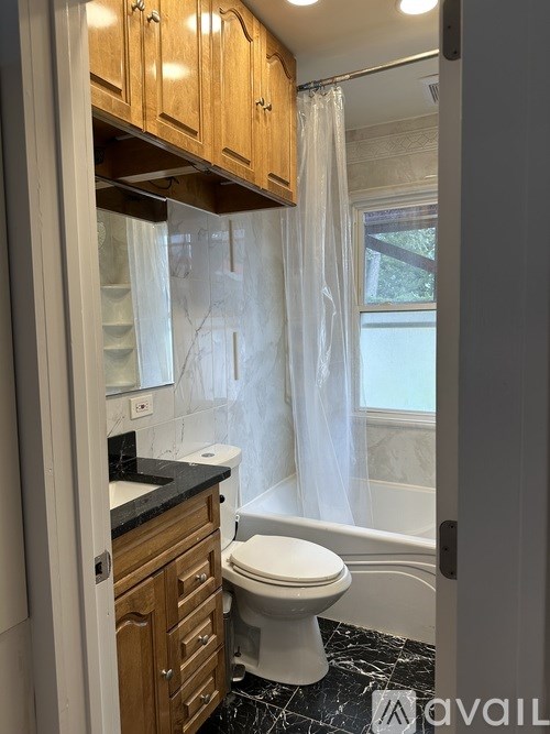 A bathroom with a toilet, sink, and wooden cabinets.