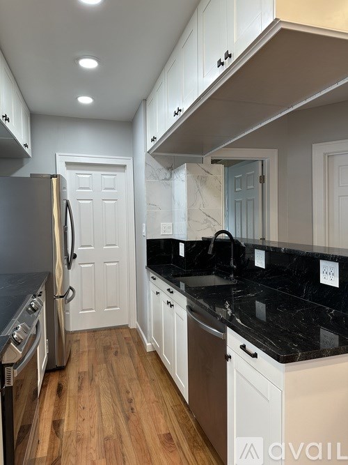 A kitchen with a black counter top and white cabinets.