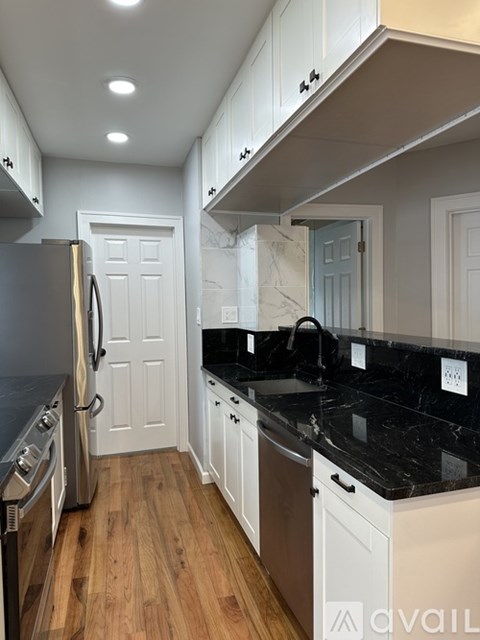 A kitchen with a black counter top and white cabinets.