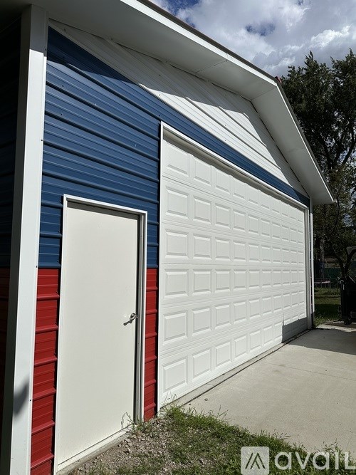 A white garage door is on the side of a blue and red building.