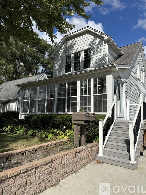 A house with a grey front porch and a brick wall.
