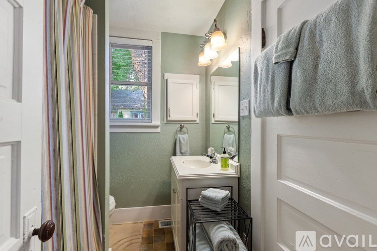 A bathroom with a striped shower curtain, a white sink, and a mirror.