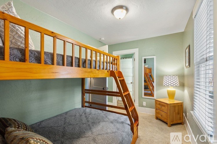 A wooden bunk bed with a ladder is in a room with green walls.