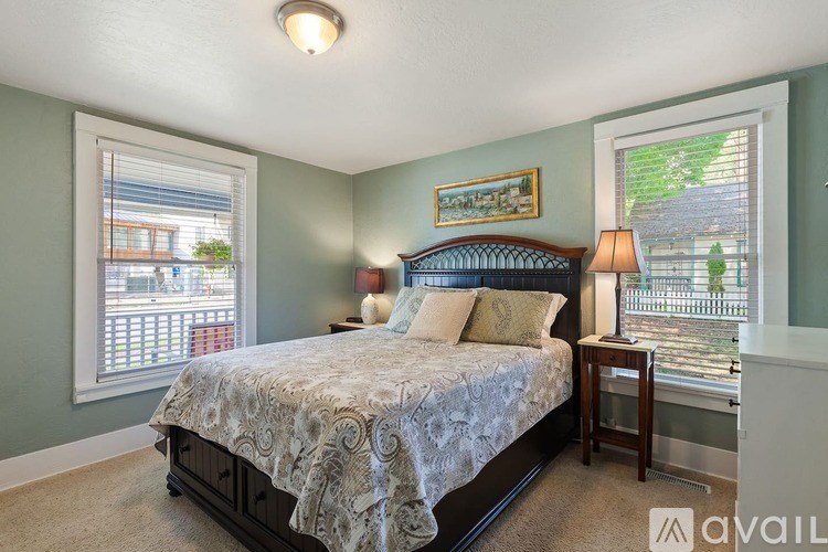 A bedroom with a bed, nightstand, and window.