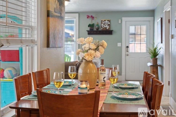 A dining table set for a meal with a vase of flowers in the middle.