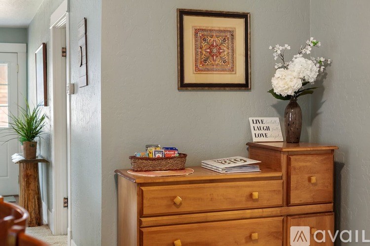 A wooden dresser with a basket, a book, and a vase with white flowers on top.