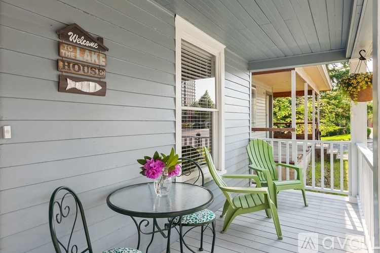 A patio with a table and chairs and a sign that says "Welcome to the Lake House".