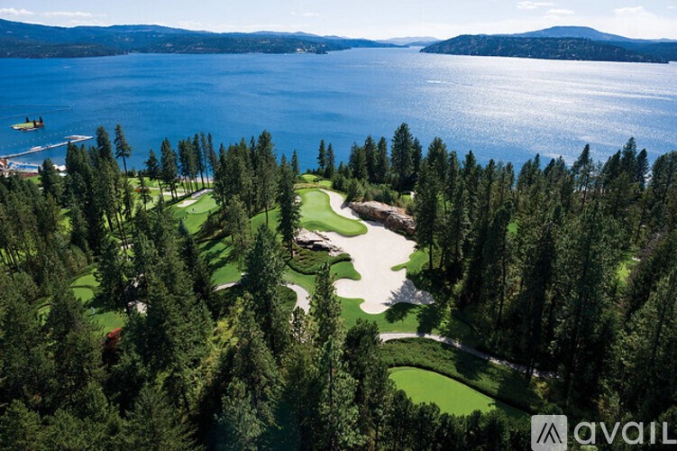 A golf course surrounded by trees and a body of water.