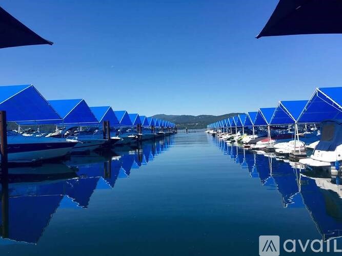 A row of boats are docked under blue canopies.
