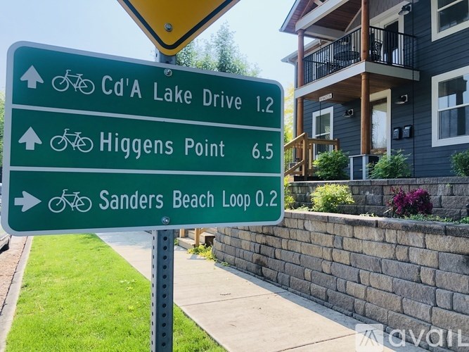 A sign shows the directions and distances to Cd'A Lake Drive, Higgins Point, and Sanders Beach Loop.