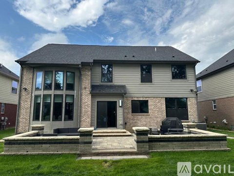 A house with a stone pillar and a black grill in the front yard.