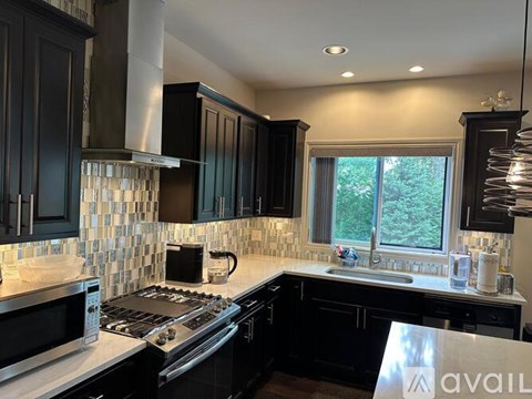 A kitchen with black cabinets and a stainless steel range hood.