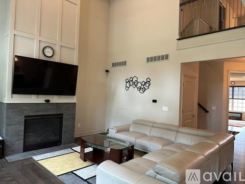 A living room with a leather couch, a fireplace, and a television.