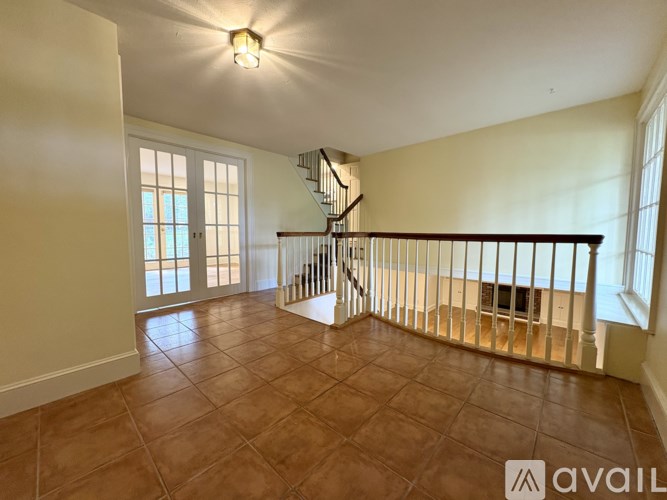 A spacious room with a tiled floor and a staircase with a metal railing.