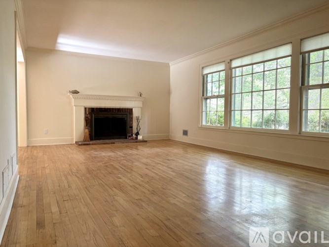 A large empty room with a fireplace and wooden floors.